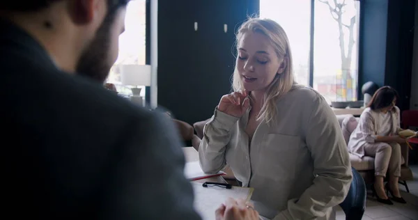 Mooi vertrouwen Kaukasische jonge blonde vrouw nemen sollicitatiegesprek met jonge mannelijke HR op zolder drukke moderne kantoor. — Stockfoto