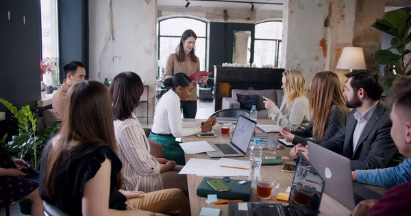 Trabajo en equipo en el moderno coworking de moda. Éxito joven morena mujer de negocios entrenador líder multiétnica oficina seminario. — Foto de Stock