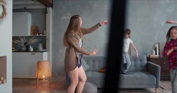 Rodinná zábava doma na uzamčené dovolené. Mladá šťastná běloška matka a dvě dospívající děti tančí, baví se bláznit. — Stock video