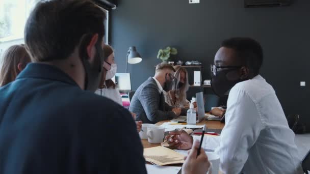 Pessoas de negócios diversa feliz usam máscaras trabalhando na mesa de escritório. Segurança como novo normal no trabalho após o término da quarentena. — Vídeo de Stock