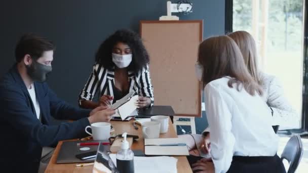 Заходи безпеки на робочому місці після закінчення карантину. Щасливі різноманітні бізнесмени носять маски, що працюють за офісним столом . — стокове відео