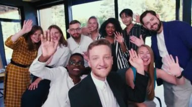 Modern ışıklı ofis işyerinde selfie grup fotoğrafı için birlikte poz veren mutlu genç iş adamlarından oluşan bir ekip..