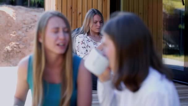 Concepto de amistad y unión. Dos jóvenes felices atractivas amigas caucásicas toman café en la terraza de la casa. — Vídeos de Stock