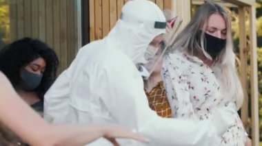 Yakın plan mutlu arkadaşlar COVID-19 güvenlik maskeleri, yüz kalkanları ve takım elbiseleriyle eğlenceli bir partide dans ediyorlar..
