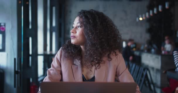 Creatividad e inspiración. Joven feliz carrera mixta freelancer femenina con el pelo rizado utilizando el ordenador portátil para el trabajo en la cafetería loft. — Vídeos de Stock