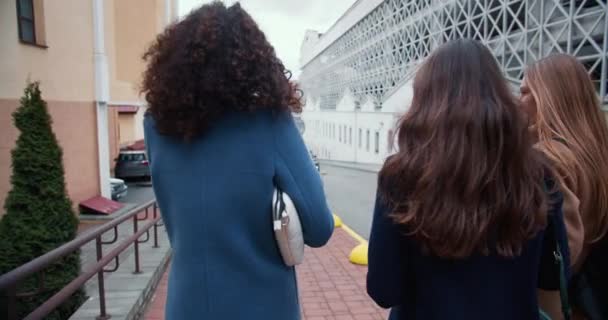 Caméra suit trois belles jeunes femmes heureuses amis marchant le long de la rue de la ville d'automne, profiter de voyager ensemble. — Video