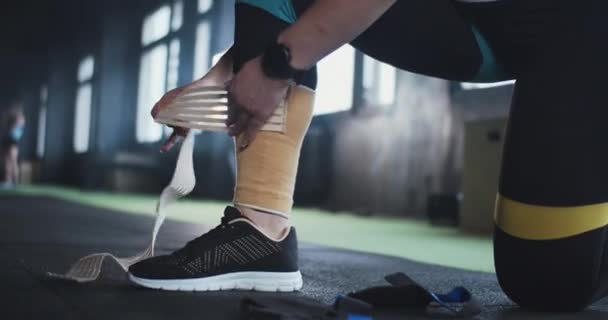Medicina e tecnologia desportiva. Atleta feminina close-up coloca fita elástica no joelho na perna, se preparando para o treino de ginástica. — Vídeo de Stock