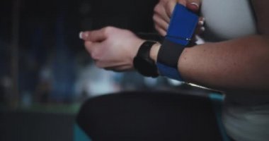 Yakın plan kadın çapraz atlet akıllı saatli koruyucu bileklikleri takıyor spor salonunda egzersiz yapmaya hazırlanıyor..