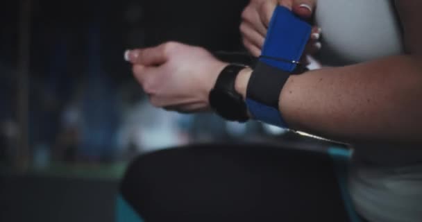 Close-up női cross fit sportoló okos óra teszi védő csukló hevederek a kezét készül gyakorolni a tornateremben. — Stock videók