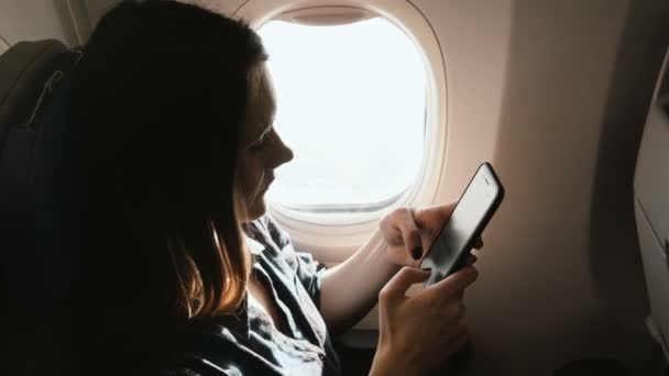 Высокоугольный крупный план молодой привлекательной ориентированной кавказской бизнесвумен с помощью приложения для покупок смартфонов на борту самолета. — стоковое видео