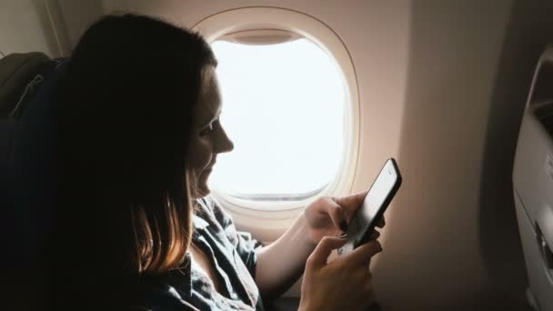 Bella foto ad alto angolo di giovane donna felice sorridente utilizzando app di intrattenimento smartphone sul volo aereo vacanza. — Video Stock