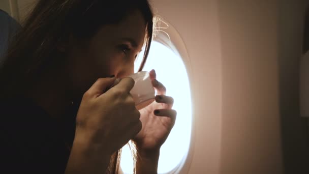 Hermosa joven relajada mujer turística europea feliz disfrutando de una bebida caliente y una increíble vista de la luz del sol en el asiento de la ventana plana. — Vídeo de stock