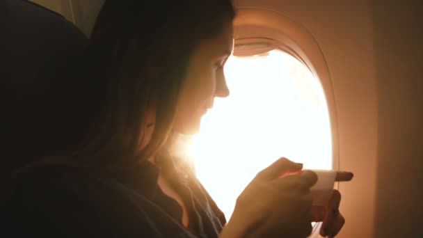 Légköri felvétel gyönyörű fiatal boldog utas nő élvezi forró ital és napos kilátás a repülőgép ablakán ülés. — Stock videók