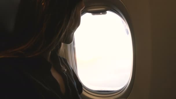 Κοντινό πλάνο της χαρούμενης επιβάτη γυναίκα απολαμβάνοντας ποτό και μεγάλη εμπνευσμένη θέα στο παράθυρο του αεροπλάνου κάθισμα κατά τη διάρκεια της πτήσης — Αρχείο Βίντεο