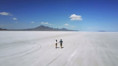 Drone romantik çiftin el ele tutuşmasını izler, Utah tuzlu çöl gölünün destansı düz arazisine doğru koşar, eğlenir..