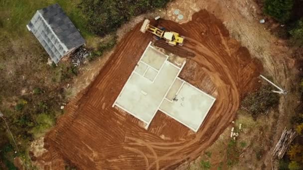 Ev temeline yukarıdan bakan havadan görüntü. Buldozer, müstakbel bir evin şantiyesinde arazi taşıyor. — Stok video