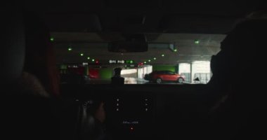 Pov içeriden vurulmuş. İki kadın, karanlık otoparkta çıkışa doğru ışıklarla şahsi araç sürerken konuşuyor..