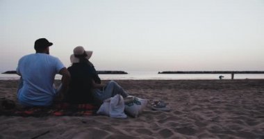 Arkaya bakan mutlu, çocuklu genç bir aile deniz kıyısında yavaş çekimde inanılmaz bir altın gün doğumu izliyorlar..