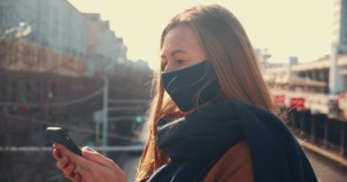 5G internet konsepti. Maskeli mutlu iş kadınının portresi dışarıda akıllı telefon uygulaması kullanıyor, kameraya gülümsüyor.