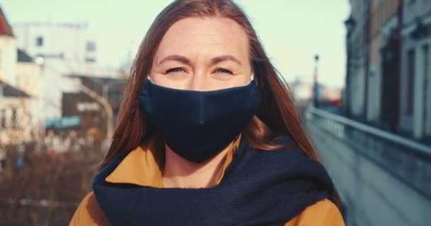 Vida após crise de coronavírus. Retrato de bela jovem mulher loira feliz sorrindo em máscara facial na ensolarada rua da cidade. — Vídeo de Stock