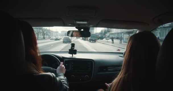 Vista trasera dentro del coche, conductor de taxi femenino en máscara facial habla con el pasajero mientras conduce y gira por las calles de la ciudad. — Vídeo de stock