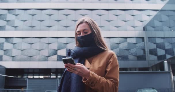 5G-Internetverbindung. Junge schöne Geschäftsfrau mit Gesichtsmaske mit Smartphone-App in futuristischem Gebäude. — Stockvideo