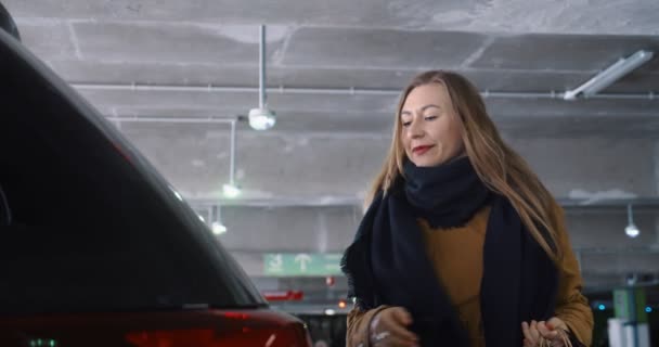 Joie de magasiner après une pandémie. Jeune belle femme heureuse ouvre le coffre de la voiture, met des sacs en papier à l'intérieur au stationnement du centre commercial. — Video