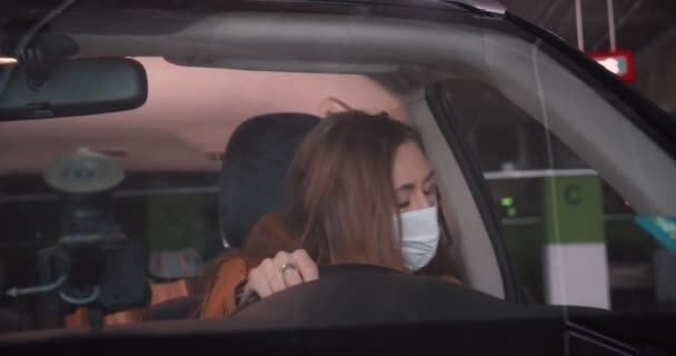 Normaal leven na afsluiting. Mooie jonge glimlachende vrouw krijgt in auto, neemt gezichtsmasker af, kijkt naar spiegel om te rijden — Stockvideo