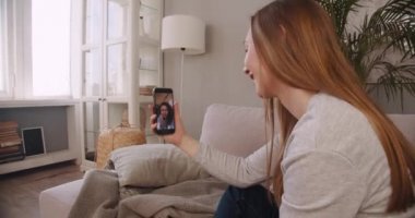 Karantinada arkadaşlık. Yan görünüm mutlu sarışın kadın akıllı telefon web konferansı aracılığıyla karışık ırk arkadaşıyla konuşuyor.