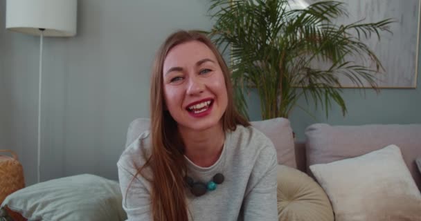 Портрет веселої жінки 30-35 років, яка посміхається білявій кавказькій жінці, говорить і махає, дивлячись на камеру. Концепція виклику відео — стокове відео
