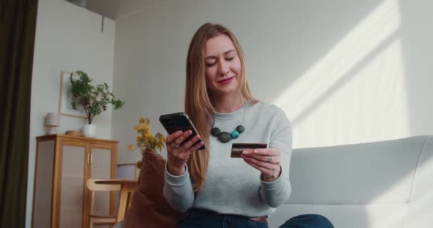 Compras adicción en línea. Hermosa mujer rubia entra en los detalles de la tarjeta en la aplicación de pago smartphone, celebra el éxito. — Vídeo de stock