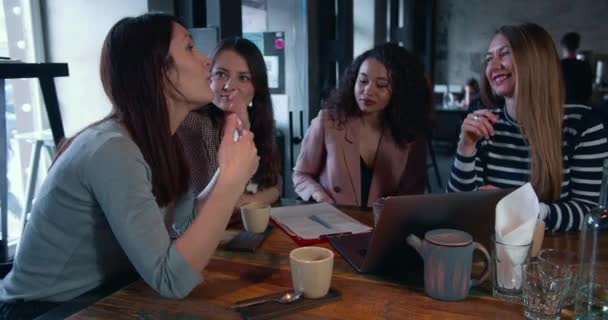Glad attraktiv ung kaukasisk kvinnlig tränare talar till tre olika leende affärskvinnor på café bord möte. — Stockvideo
