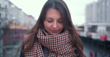 Güzel, mutlu, heyecanlı, 30-35 arası esmer, beyaz bir kadının portresi. Şehir sokaklarında yavaş çekimde kameraya gülümsüyor..