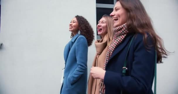 Ocio de fin de semana. Tres jóvenes y felices amigas atractivas disfrutando del tiempo juntas, caminando por la muralla del edificio de la ciudad. — Vídeos de Stock