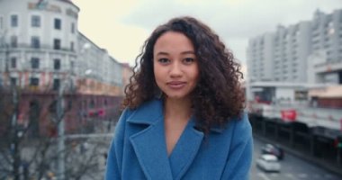 Güzel, mutlu, Afro-Amerikan melez, kıvırcık saçlı kadının portresi. Köprüde ağır çekimde poz veriyor..