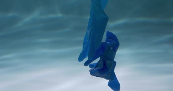 汚染された海でのパンデミックの結果。水の遅い動きの下に浮かぶ青の医療用手袋を使い捨て. — ストック動画