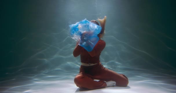 Neopatrné použití plastu. Mladá žena vyhazuje odpadkový pytel s lahvičkami na jedno použití, tašky pod vodou zpomalené. — Stock video