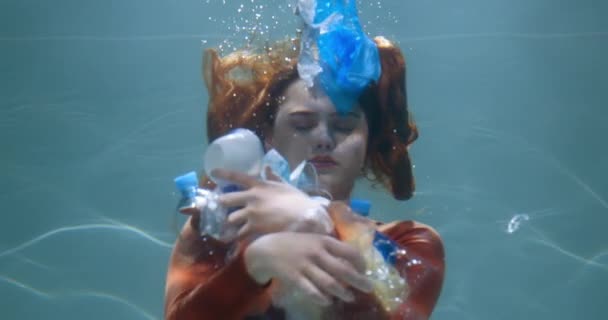 Plastikverschmutzung der Ozeane. Junge Frau verteilt Einwegmüll unter Wasser, Abfall schwimmt in Zeitlupe. — Stockvideo