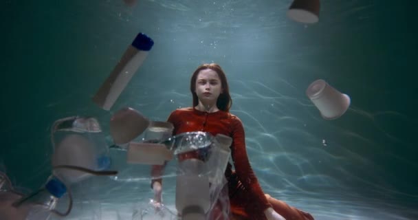 Inquinamento plastico dell'oceano. Scatto cinematografico di modella in posa sott'acqua, bottiglie galleggianti intorno al rallentatore. — Video Stock
