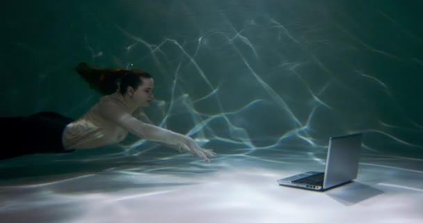 Koncepcja asystenta online. Atrakcyjny młody biznes kobieta pływa pod wodą, aby korzystać z laptopa i skonsultować się z klientem slow motion. — Wideo stockowe