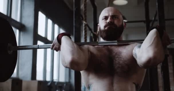 Primer plano joven atleta caucásico hombre levantar pesadas barras en gran sala de gimnasio hardcore. Concepto de ambición y desafío. — Vídeo de stock