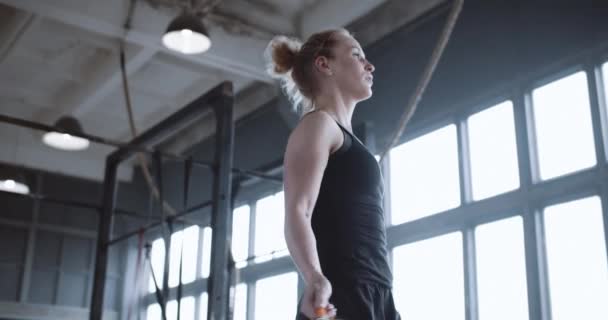Nízký úhel boční pohled krásný mladý šťastný atletický blondýnka žena pracuje se skákat provaz ve velké tělocvičně zpomalení. — Stock video