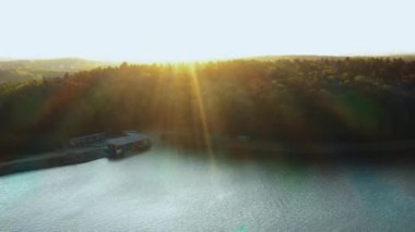 Muhteşem doğa ve kentsel ufuk çizgisi, insansız hava aracı sakin sonbahar gölünden sağa dönüyor ve yeşil orman şehir binalarına doğru ilerliyor..