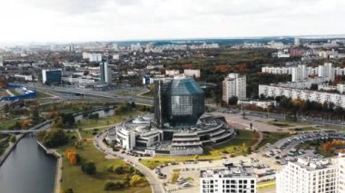 İnsansız hava aracı Belarus, Minsk Ulusal Kütüphanesi 'nden güzel bir sonbahar şehir panoramasına ve megapolis gelişmesine doğru hızla uzaklaşıyor..