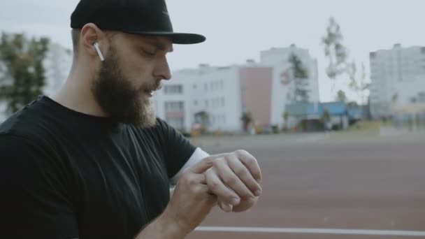 Junge glückliche Amateur-Sportler immer bereit, auf Outdoor-Leichtathletik laufen, Einstellung Timer auf Smartwatch Zeitlupe. — Stockvideo