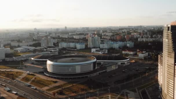 Drona care zboară în jurul stadionului orașului Minsk Arena, panorama urbană a Belarusului în timpul răsăritului de soare maiestuos în ziua senină de toamnă . — Videoclip de stoc