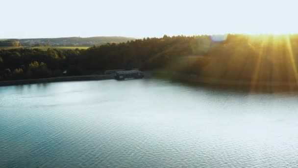 信じられないほどの日没の自然、秋の湖、緑の森、遠くの都市のスカイラインを反映して穏やかに右に曲がるドローン. — ストック動画