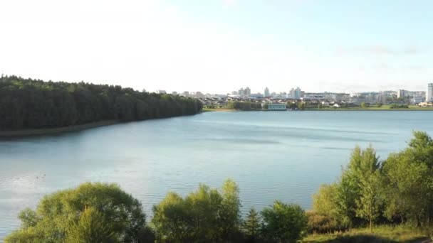 Natureza magnífica perto do horizonte urbano, drone virando à direita acima do lago de outono e floresta verde em direção a edifícios da cidade. — Vídeo de Stock