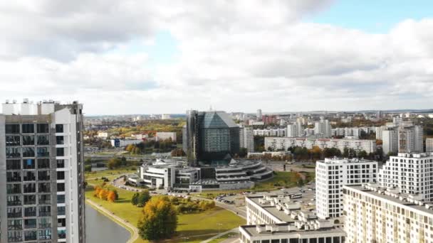 Drone volando a la izquierda alrededor de la Biblioteca Nacional de Belarús, Minsk. Monumento famoso y bloques de apartamentos en construcción. — Vídeos de Stock