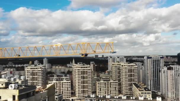 Drone volando muy cerca alrededor de la grúa de construcción de edificios amarillos durante el proceso de desarrollo del bloque de torre de gran altura. — Vídeos de Stock